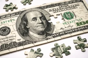 A jigsaw puzzle made from a hundred-dollar bill, representing the holistic benefits of comprehensive wealth management