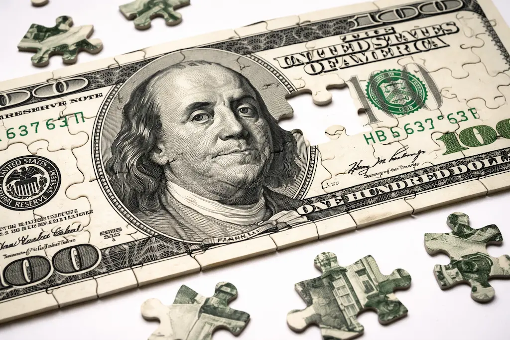 A jigsaw puzzle made from a hundred-dollar bill, representing the holistic benefits of comprehensive wealth management