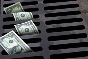 Dollar bills going down the a storm drain