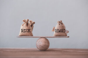 Risk and reward bags on a basic balance scale in equal position on wood table.