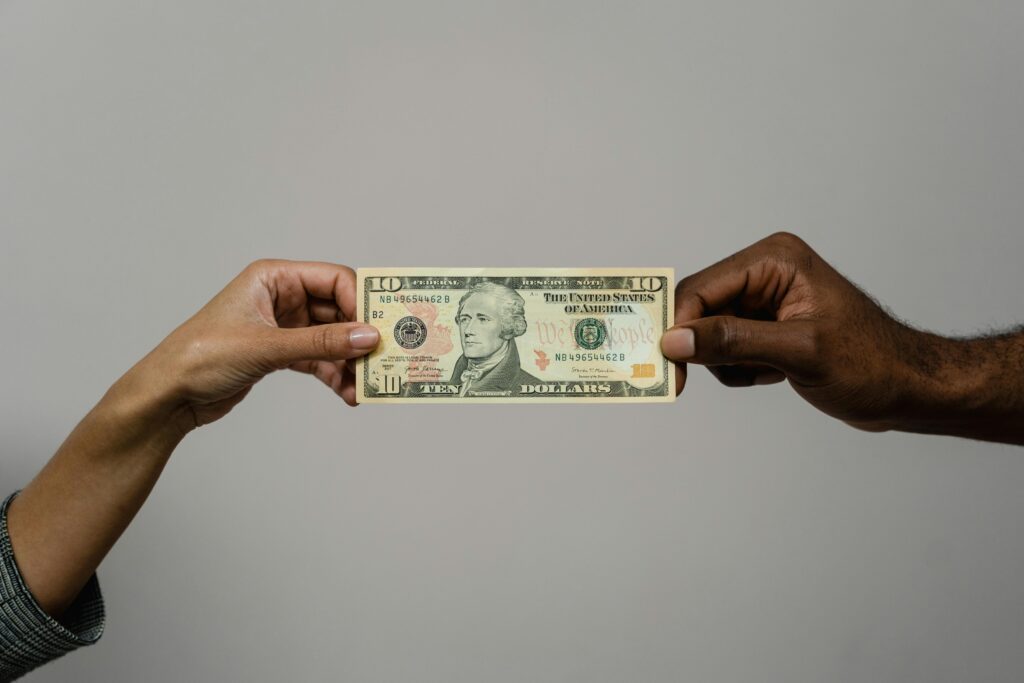 Two Hands Holding Same Dollar Bill